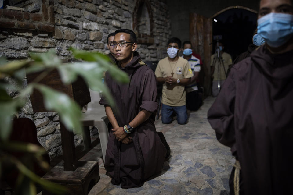 Seminarist Oveniel Garcia, 21, left, kneels during a Mass celebrated by Friar Leopoldo Serrano in the chapel at Mission San Francisco de Asis, Honduras, Saturday, June 19, 2021. Garcia, a former drug addict and trafficker, entered the rehab center at the mission run by Serrano. Over the years, he became Serrano’s right-hand man. (AP Photo/Rodrigo Abd)