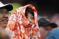 A spectator uses a promotional Hawaiian shirt giveaway to protect against light rain during the sixth inning of a baseball game between the Baltimore Orioles and the Los Angeles Angels, Saturday, July 9, 2022, in Baltimore. The Orioles won 1-0. (AP Photo/Julio Cortez)