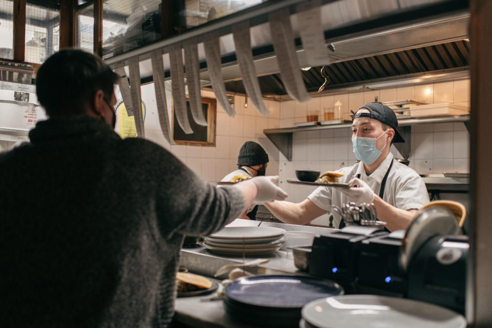 NEW YORK, NY - FEBRUARY 12: Masked kitchen workers pass finished plates of food to a server at Claro restaurant on February 12, 2021 in New York City. New rules allow restaurants, bars, and cafes to reopen at 25% capacity due to the ongoing coronavirus pandemic. (Photo by Scott Heins/Getty Images)