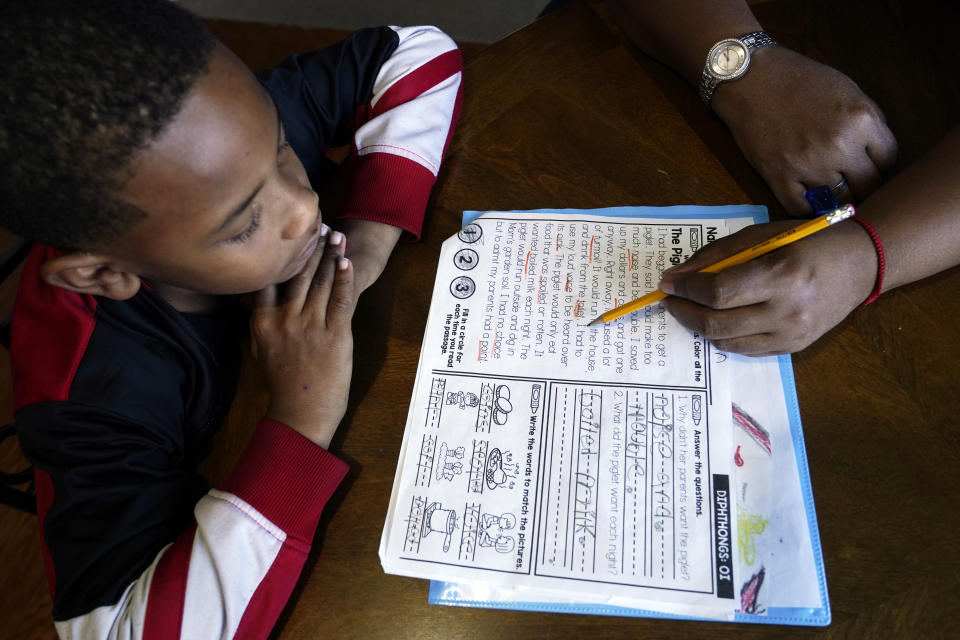 Christian Ensrud, 7, watches as his mother, Tamela Ensrud, help him with his homework at their home Monday, Nov. 21, 2022, in Nashville, Tenn. As parents try to help their children recover from several years of interrupted learning, some are struggling to get clear information explaining how their children are performing or a school plan to help them catch up on the learning they missed. (AP Photo/Mark Humphrey)