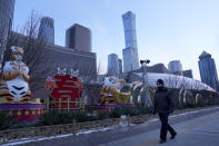 A resident past by 2022 Chinese Lunar New Year of the Tiger decorations at the central business district in Beijing, China, Wednesday, Jan. 26, 2022. Richer, more heavily armed and openly confrontational, China has undergone history-making change since the last time it was an Olympic host in 2008. (AP Photo/Ng Han Guan)