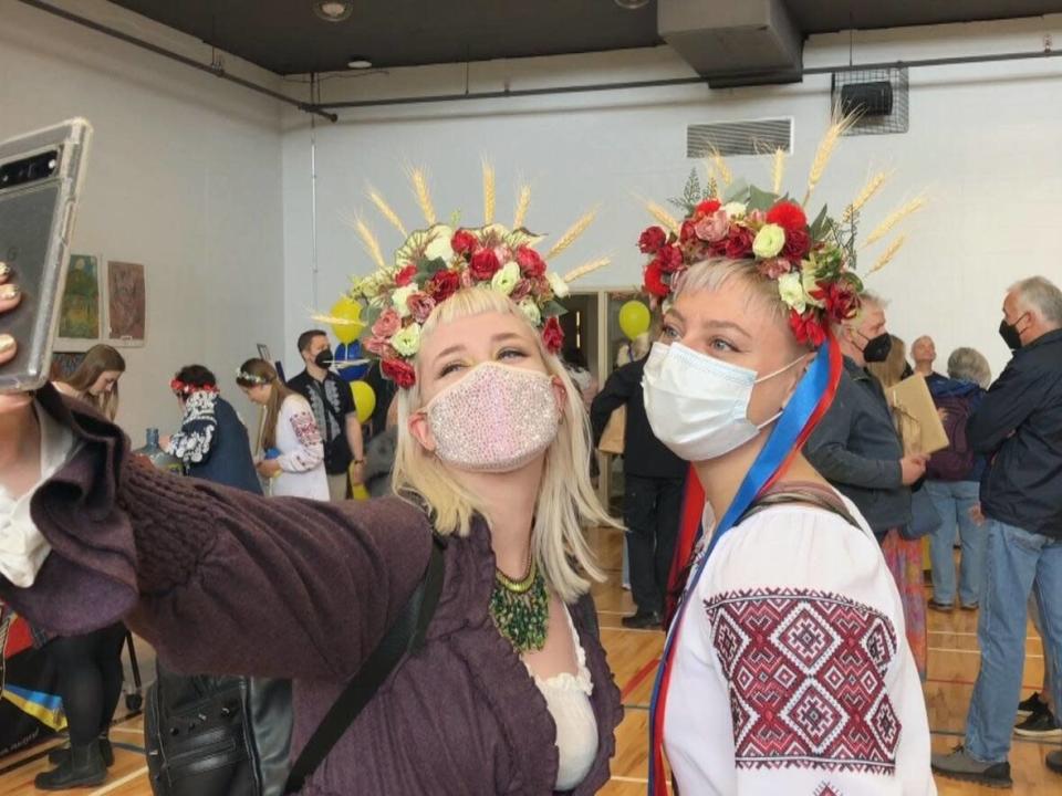 Amanda Hobbs, left, and Taylor Barei take photos wearing traditional head pieces created by Barei during the fundraiser for Ukraine in Halifax on April 23, 2022.  (CBC - image credit)