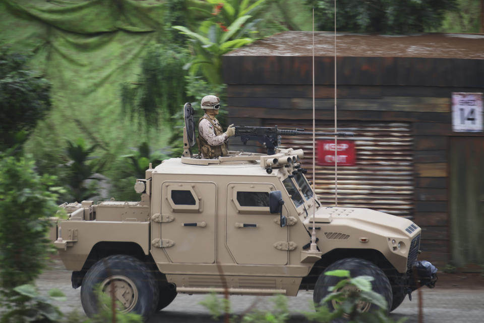 Soldiers in an attack vehicle drive by other troops during a military demonstration at the International Defense Exhibition and Conference in Abu Dhabi, United Arab Emirates, Sunday, Feb. 17, 2019. The biennial arms show in Abu Dhabi comes as the United Arab Emirates faces increasing criticism for its role in the yearlong war in Yemen. (AP Photo/Jon Gambrell)