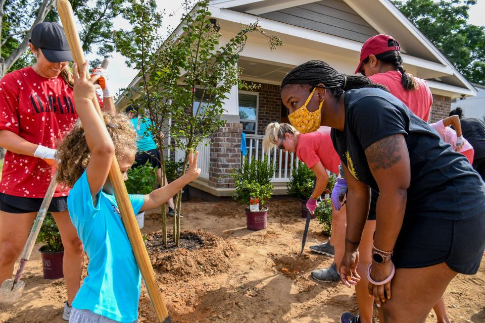 Aug 10, 2022; Tuscaloosa, AL, USA; Wives of University of Alabama's football coaching staff do the landscaping work for the Habitat for Humanity house that was funded by the Nick's Kids Foundation on Ash Street in Tuscaloosa, Wednesday, Aug. 10, 2022. Four-year-old Wynn Williams shows how old she is to homeowner Kanika Cotton. Gary Cosby Jr.-Tuscaloosa News