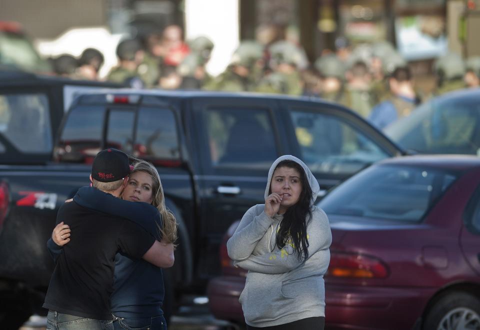 Students hug each other and wait outside Arapahoe High School after being escorted out of the building in Centennial, Colorado