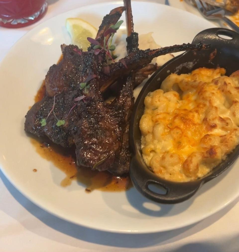 A plate of lamb chops next to mac and cheese on a dining table, indicative of local cuisine