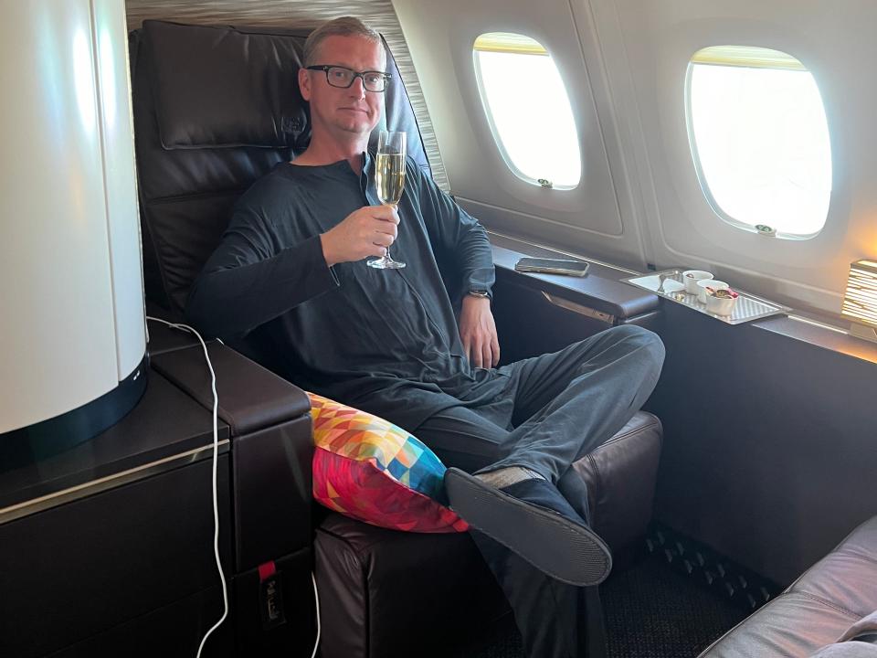 man sitting in first class on an airplane with a glass of champagne