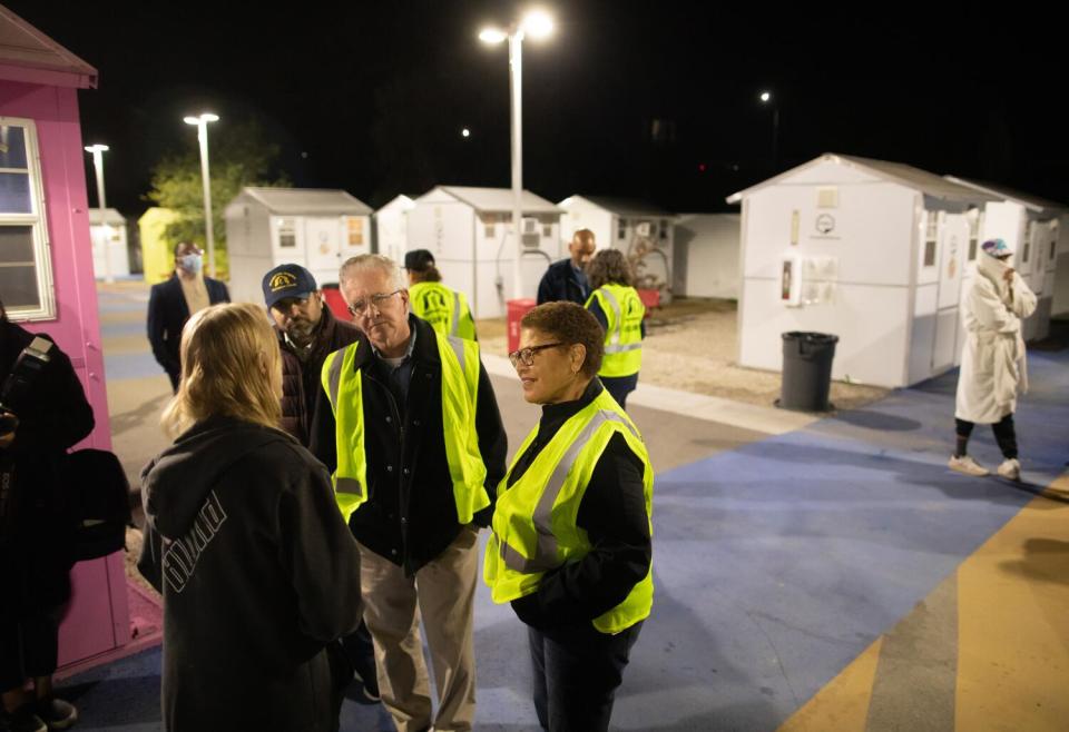 Paul Krekorian and Karen Bass speak with a woman amid tiny homes