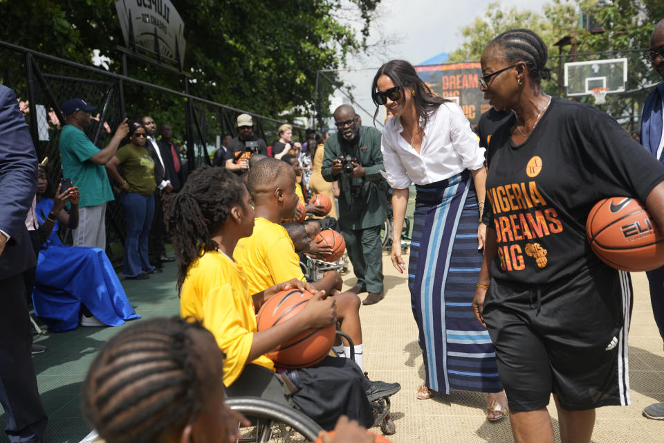 Meghan Markle, centre, Speaks with children on a wheelchair during the Giant of Africa Foundation at the Dream Big Basketball clinic in Lagos Nigeria, Sunday, May 12, 2024. Prince Harry and his wife Meghan are in Nigeria to champion the Invictus Games, which Prince Harry founded to aid the rehabilitation of wounded and sick servicemembers and veterans. (AP Photo/Sunday Alamba)