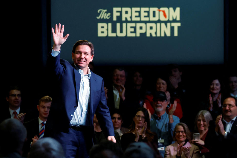 Florida Gov. Ron DeSantis waves to his audience in front of a screen saying: The Freedom Blueprint, the title of his book.