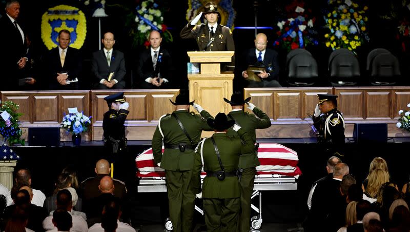 Officers salute as the casket is brought in for funeral services for Santaquin Police Sgt. Bill Hooser in the UCCU Center at UVU in Orem on Monday.  Michael Aaron Jayne was charged with Hooser's murder on Tuesday.