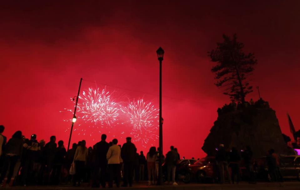 People watch as fireworks explode over the coast of Vina del Mar, Chile as part of the New Year celebrations, January 1, 2013.