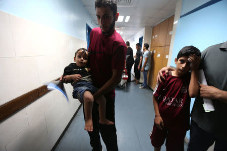 Palestinian boys are brought into the hospital following Israeli air strikes in Gaza City July 14, 2018. REUTERS/Ibraheem Abu Mustafa