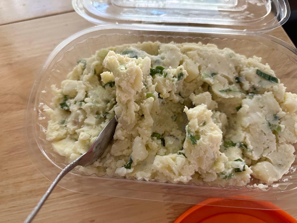 potato salad and green onion in plastic container with fork in it