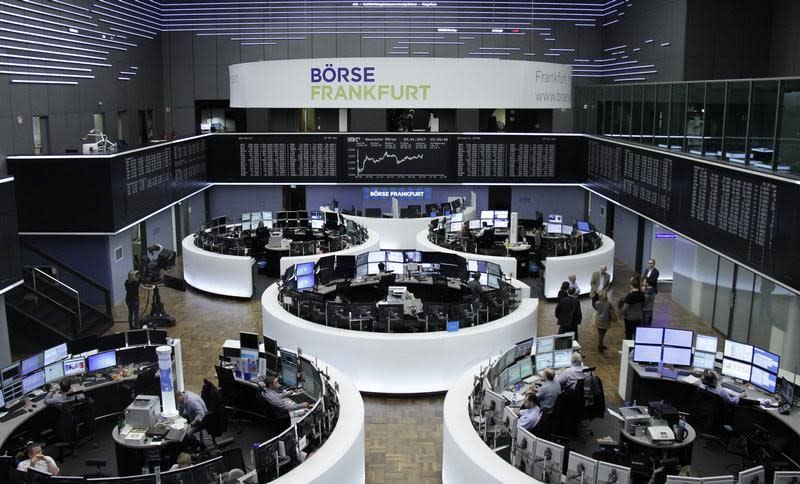 Traders work at their desks in front of the German share price index, DAX board, at the stock exchange in Frankfurt, Germany, January 20, 2017. REUTERS/Staff/Remote