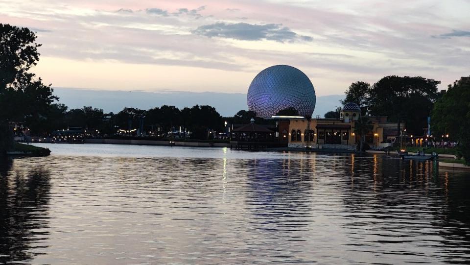 EPCOT's Spaceship Earth in the distance behind a lake of glimmering water at dusk