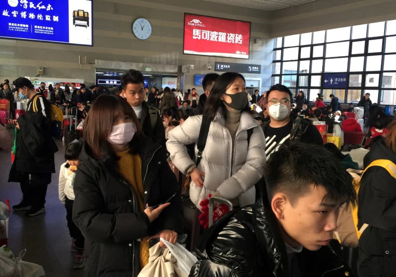 Passengers wearing masks wait to board trains at the Beijing West Railway Station, in Beijing