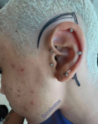 Close-up of the scythe tattoo behind Doja's ear