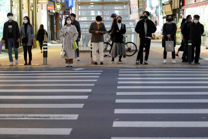 People wearing masks to prevent contracting the coronavirus wait for a signal at a zebra crossing at Dongseong-ro shopping street in central Daegu