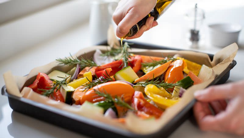 Seasoning a tray of vegetables for roasting with olive oil is pictured in this undated image. Many adults find it tough to incorporate vegetables into their diet.