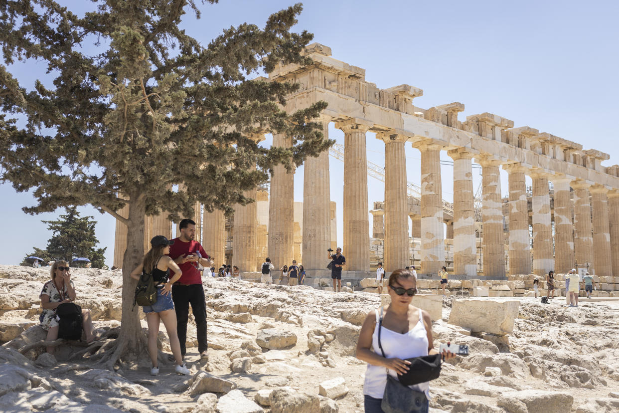 18 June 2024, Greece, Athen: Tourists sit in the shade under a tree during their visit to the Acropolis. Greece has been hit by extreme heat particularly early this year: According to meteorologists, it has never been this hot since records began in early June. Temperatures reached up to 40 degrees at times - and even higher in the blazing midday sun. Photo: Socrates Baltagiannis/dpa (Photo by Socrates Baltagiannis/picture alliance via Getty Images)