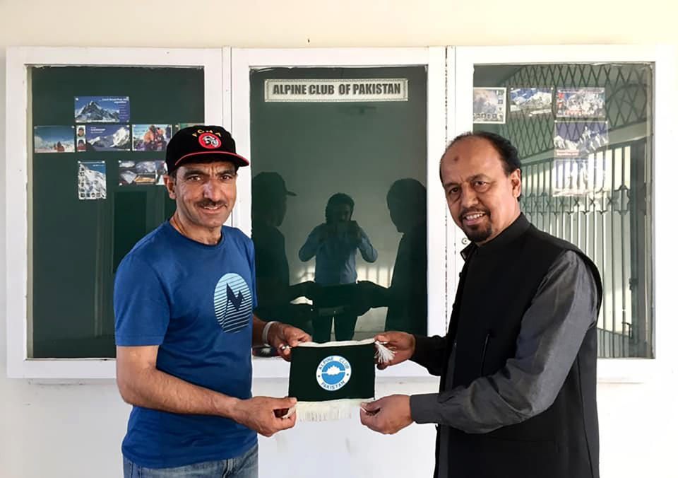 In this 2018 photo provided by Alpine Club of Pakistan shows, Pakistani mountaineer Ali Sadpara, left, receives a souvenir from Karrar Haider, a top official of Alpine Club of Pakistan, at his office in Islamabad, Pakistan. An aerial search mission is on to find three experienced climbers, Sadpara and his two companions, John Snorri and Juan Pablo Mohr, who lost contact with the base camp during their ascend on world's second top peak in northern Pakistan, official said Sunday, Feb. 7, 2021. (Alpine Club of Pakistan via AP)