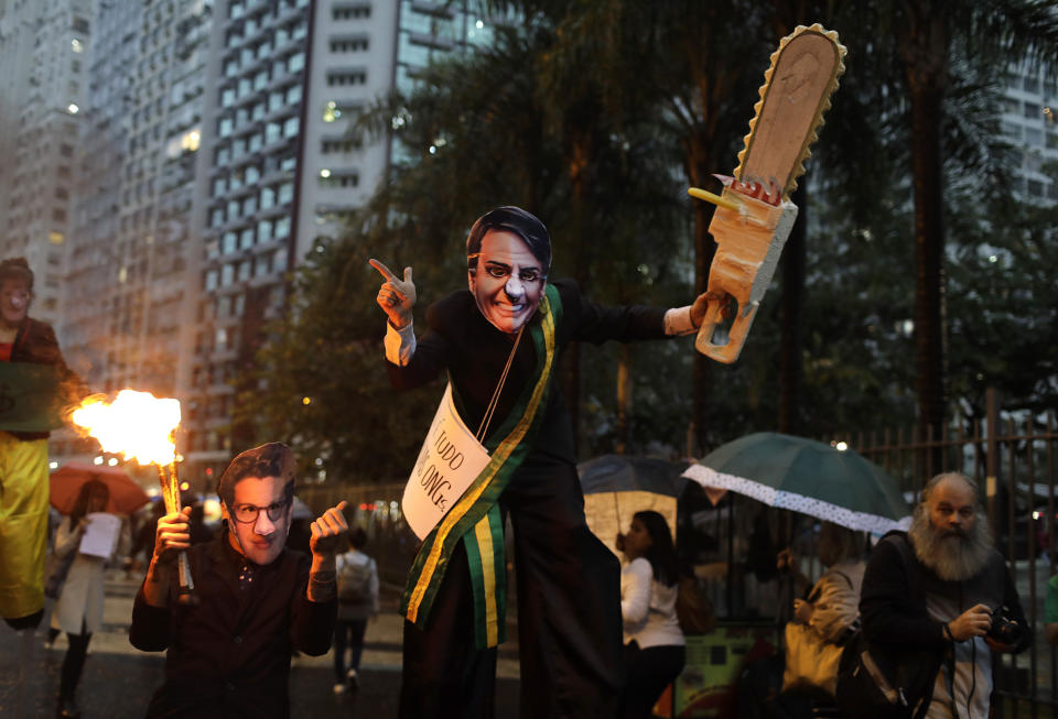 A demonstrator wearing a Brazilian President Jair Bolsonaro mask and brandishing a fake chainsaw, center, with another wearing a mask o Brazil's Environment Minister Ricardo Salles, march in defense of the Amazon in Rio de Janeiro, Brazil, Thursday, Sept. 5, 2019. Bolsonaro will not attend a reunion of regional leaders whose countries include parts of the Amazon rainforest that is scheduled for Friday in Colombia, with government spokesman Otavio Rego Barros saying the president could not go because of upcoming surgery to treat a hernia. Bolsonaro was stabbed in the abdomen during the presidential campaign. (AP Photo/Silvia Izquierdo)