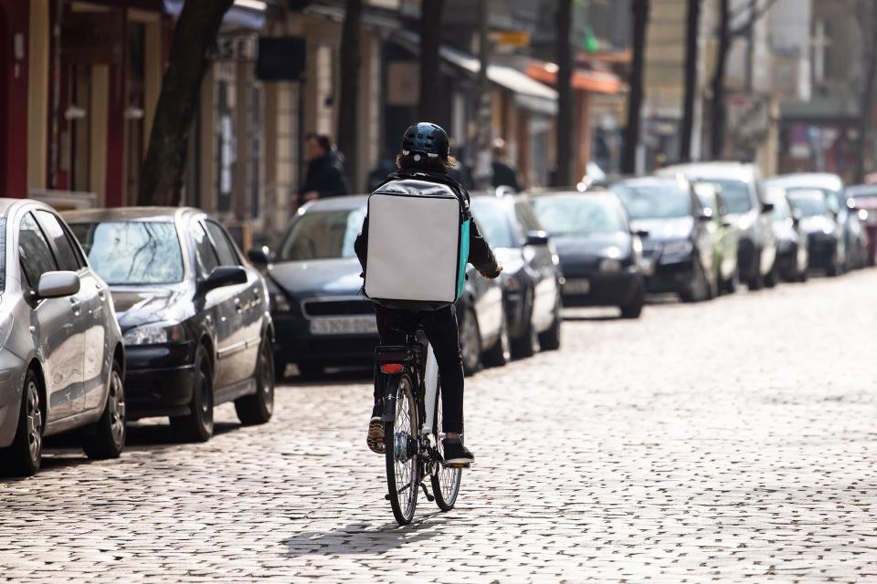 A food delivery person with a thermal backpack riding a bike on the street