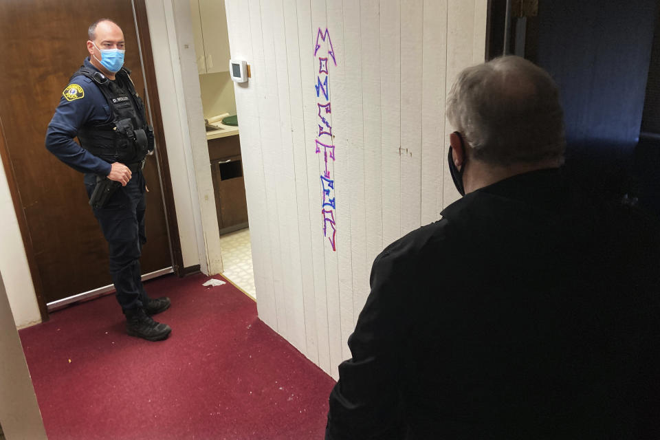 Lynnwood police Officer Denis Molloy, left, talks with the property manager, right, Wednesday, Nov. 17, 2021, at an office complex in Lynnwood, Wash., that had been burglarized and littered with trash and drug-use paraphernalia. Molloy, of the Lynnwood Police Department's community health and safety section, says that navigating recent police reforms in Washington State has been challenging. (AP Photo/Gene Johnson)