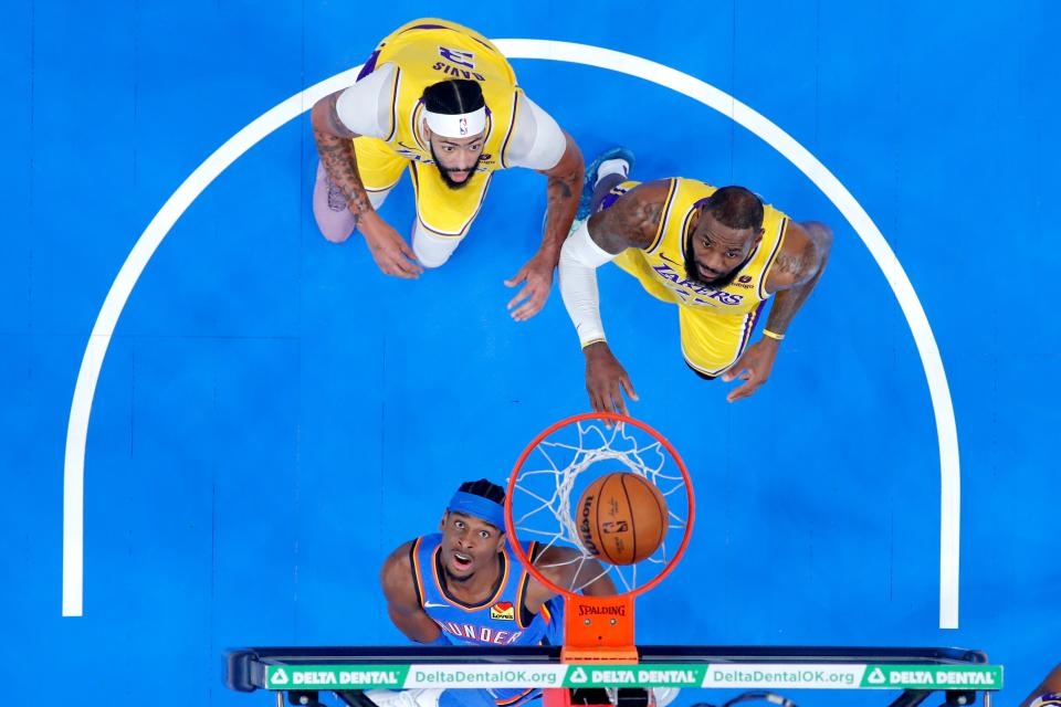 Oklahoma City Thunder guard Shai Gilgeous-Alexander (2) watches his shot pgo in in front of Los Angeles Lakers forward Anthony Davis, left, and forward LeBron James during an NBA basketball game between the Oklahoma City Thunder and the Los Angeles Lakers at Paycom Center in Oklahoma City, Thursday, Nov. 30, 2023. Oklahoma City won 133-110.