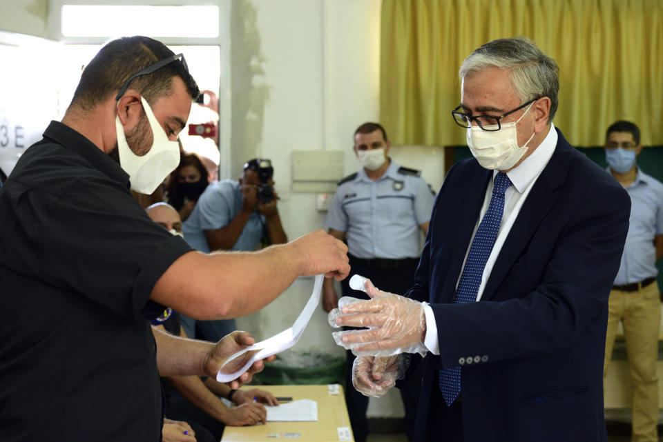 In this photo taken on Sunday, Oct. 11, 2020, Turkish Cypriot leader and candidate Mustafa Akinci casts his ballot at a polling station during the Turkish Cypriots election for a new leader in the Turkish occupied area in the north part of the divided capital Nicosia, Cyprus, Sunday, Oct. 11, 2020. Turkish Cypriots vote on Sunday Oct. 18, 2020 in a leadership runoff that could decide if they want to retain more control over their own affairs or steer even closer to an increasingly domineering Turkey. (AP Photo/Nedim Enginsoy)