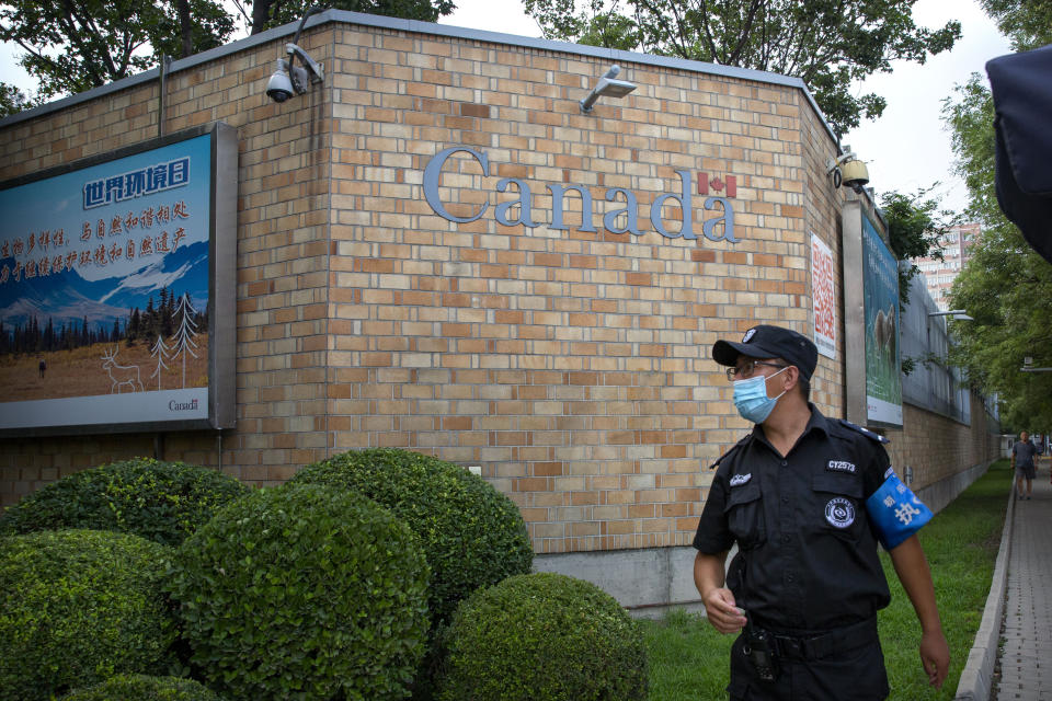 FILE - In this Aug. 6, 2020, a security officer wearing a face mask to protect against the coronavirus stands outside the Canadian Embassy in Beijing. A Canadian entrepreneur who was charged with spying after his government arrested an executive of Chinese tech giant Huawei faces a possible verdict Wednesday, Aug. 11, 2021 as Beijing steps up pressure on Canada ahead of a court ruling on whether to hand over the executive to face U.S. criminal charges. (AP Photo/Mark Schiefelbein, File)