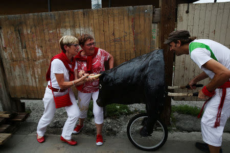 Women try to fend off a toy bull as they watch the Encierro Txiki (Little Bull Run) during the San Fermin festival in Pamplona, northern Spain, July 10, 2017. REUTERS/Susana Vera