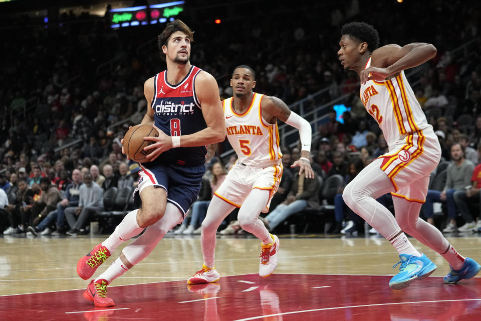 Washington Wizards forward Deni Avdija (8) drives against Atlanta Hawks' Dejounte Murray (5) and De'Andre Hunter (12) during the first half of an NBA basketball game, Wednesday, Nov. 1, 2023, in Atlanta. (AP Photo/John Bazemore)