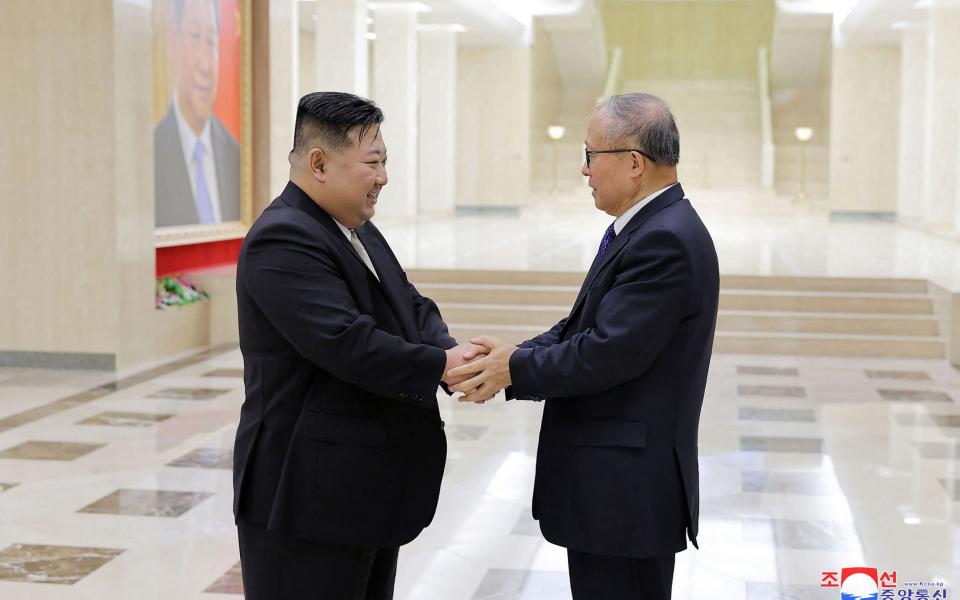 North Korea's leader Kim Jong Un shaking hands with China's Communist Party politburo member Li Hongzhong