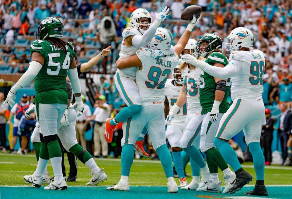 Miami Dolphins linebacker Duke Riley (45) jumps on Miami Dolphins defensive tackle Zach Sieler (92) as they celebrate after Sieler recovers New York Jets quarterback Zach Wilson (2) fumble in the first quarter at Hard Rock Stadium in Miami Gardens, Florida on Sunday, December 17, 2023.