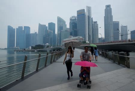 People pass skyline of Singapore's central business district shrouded by haze August 26, 2016. REUTERS/Edgar Su