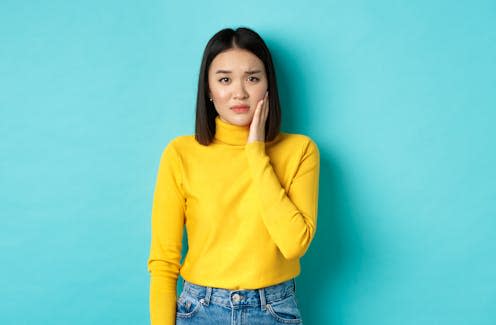 <span class="caption">A racist slur can create pain comparable to a slap in the face.</span> <span class="attribution"><a class="link " href="https://www.shutterstock.com/image-photo/portrait-asian-young-woman-touching-cheek-1892774038" rel="nofollow noopener" target="_blank" data-ylk="slk:Mix and Match Studio/Shutterstock;elm:context_link;itc:0;sec:content-canvas">Mix and Match Studio/Shutterstock</a></span>