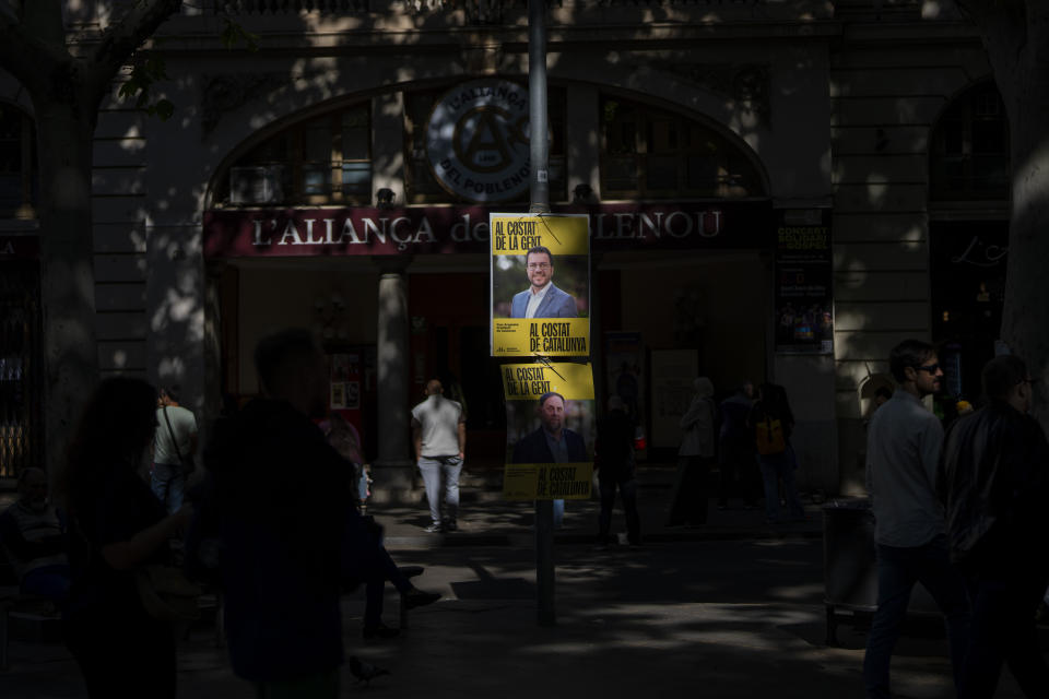 People walk past electoral posters showing a portrait of Catalan president and ERC candidate Pere Aragonès in downtown Barcelona, Spain, Thursday, May 9, 2024. Some nearly 6 million Catalans are called to cast ballots in regional elections on Sunday that will surely have reverberations in Spain's national politics. (AP Photo/Emilio Morenatti)