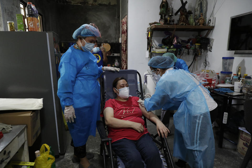 A health worker inoculates a resident with China's Sinovac COVID-19 vaccine inside her home in Manila, Philippines on Wednesday, May 19, 2021. Philippine President Rodrigo Duterte has eased a lockdown in the bustling capital and adjacent provinces to fight economic recession and hunger but has still barred public gatherings this month, when many Roman Catholic festivals are held. (AP Photo/Aaron Favila)