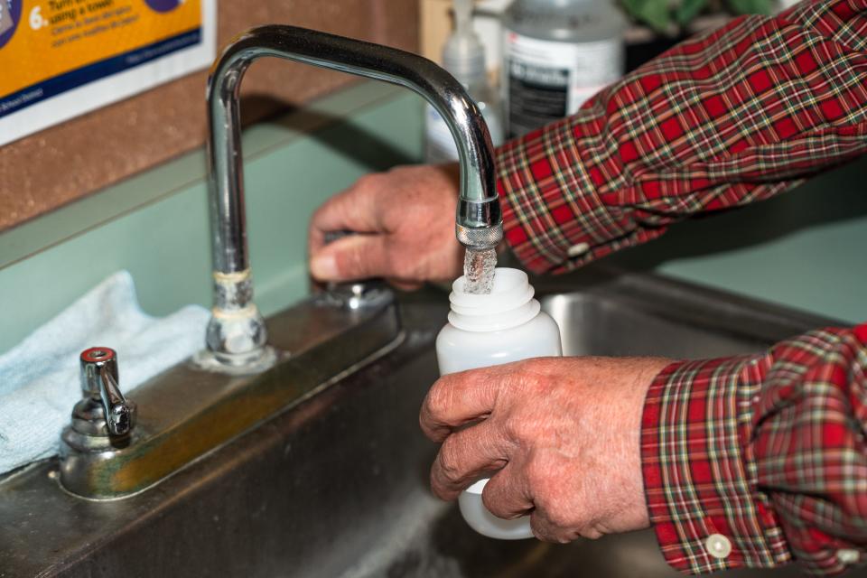 John Holcombe, environmental coordinator for Poudre School District, collects a water sample from a faucet at Johnson Elementary School on March 30, 2023, in Fort Collins.