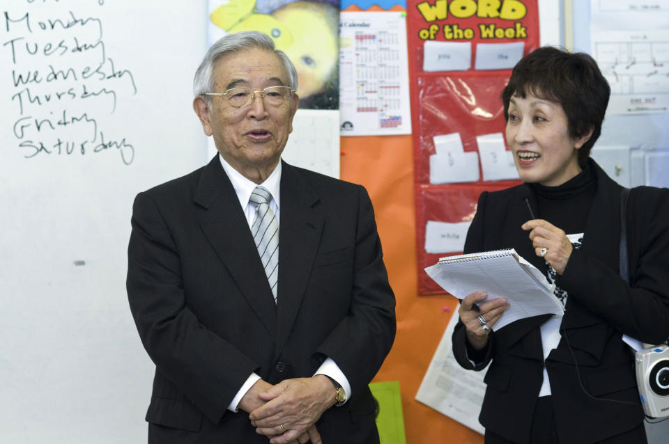 FILE - Dr. Shoichiro Toyoda, center, then honorary chairman of Toyota with his translator Ms. Morita, left, speaks to a classroom at St. Bartholomew School Monday, April 4, 2011, in Louisville, Ky., during a tour to observe students and parents participating in Toyota's Family Literacy Program. Toyoda, who as a son of the company's founder oversaw Toyota's expansion into international markets has died. He was 97. (AP Photo/Brian Bohannon, File)