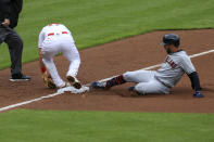 Cincinnati Reds' Kyle Farmer, second from right, attempts to field the ball as Cleveland Indians' Eddie Rosario, right, slides safely into third base after hitting an RBI-triple during the third inning of a baseball game in Cincinnati, Saturday, April 17, 2021. (AP Photo/Aaron Doster)