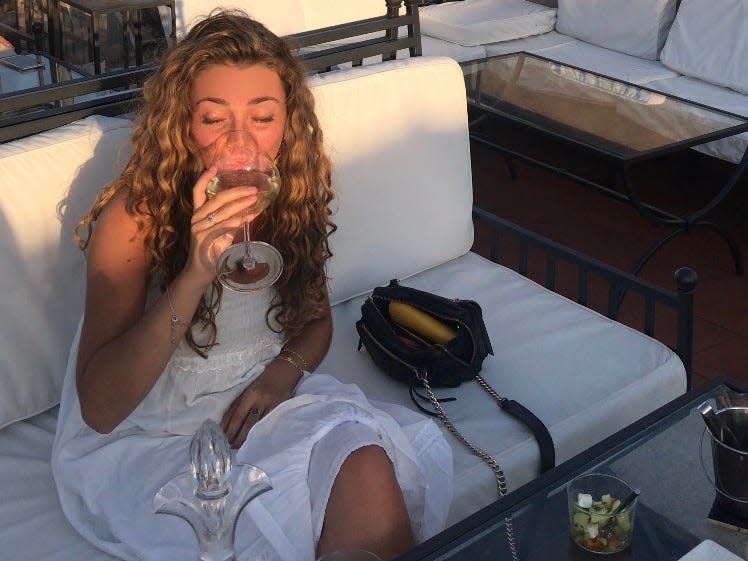 woman on rooftop bar in rome, italy drinking a glass of wine