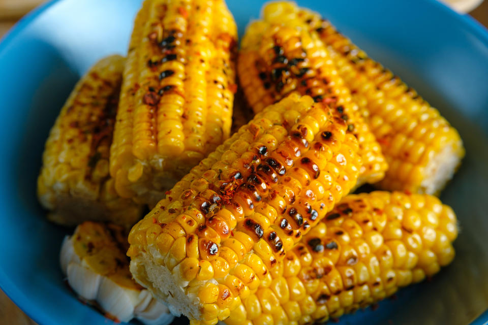 Grilled corn on the cob served in a blue bowl. No people are present in the image