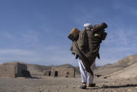 Hajji Wali Jan, 66, carries plastic containers for water on his way to his house in Kamar Kalagh village outside Herat, Afghanistan, Friday, Nov. 26, 2021. Afghanistan’s drought, its worst in decades, is now entering its second year, exacerbated by climate change. (AP Photo/Petros Giannakouris)