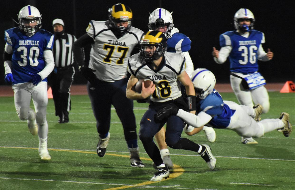 Tioga quarterback Caden Bellis (18) is grabbed from behind by Dolgeville Blue Devil Brett Mosher during the first half of the 2022 Class D regional playoff game at Michael J. Bragman Stadium in Cicero. Dolgeville and Tioga meet again Friday in Vestal.