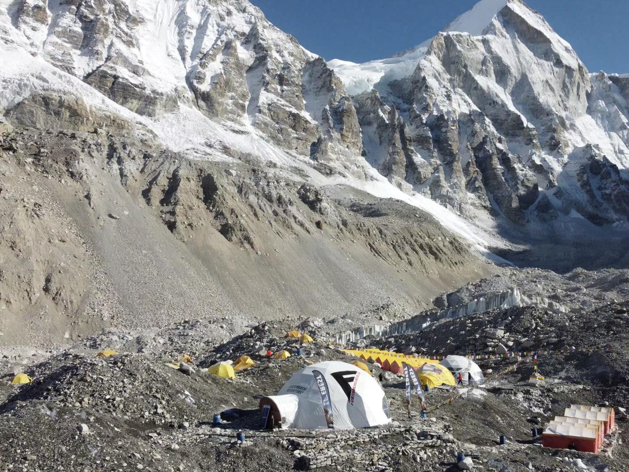 A group of tents set up around the base of a large snowcapped mountain.