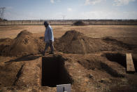 A worker walks past a freshly-dug graves at the Honingnestkrans Cemetery, North of Pretoria, South Africa, Thursday, July 9, 2020. The Africa Centers for Disease Control and Prevention says the coronavirus pandemic on the continent is reaching "full speed" after cases surpassed a half-million and a South African official said a single province is preparing 1.5 million grave. (AP Photo/Shiraaz Mohamed)