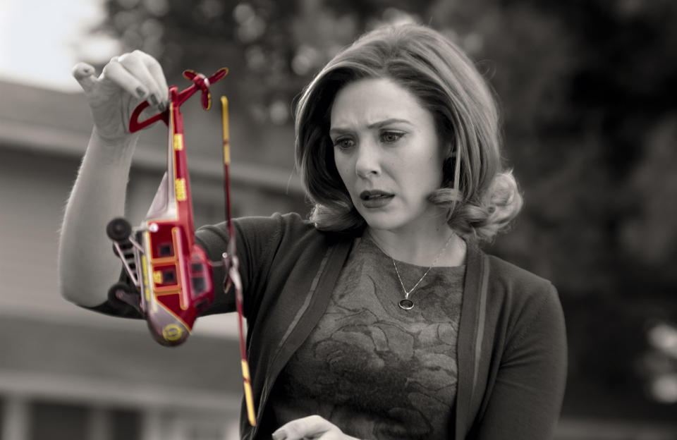 Black-and-white still of a woman in 1950s clothing holding up a toy helicopter in shock, but the helicopter is in color; still from "WandaVision"